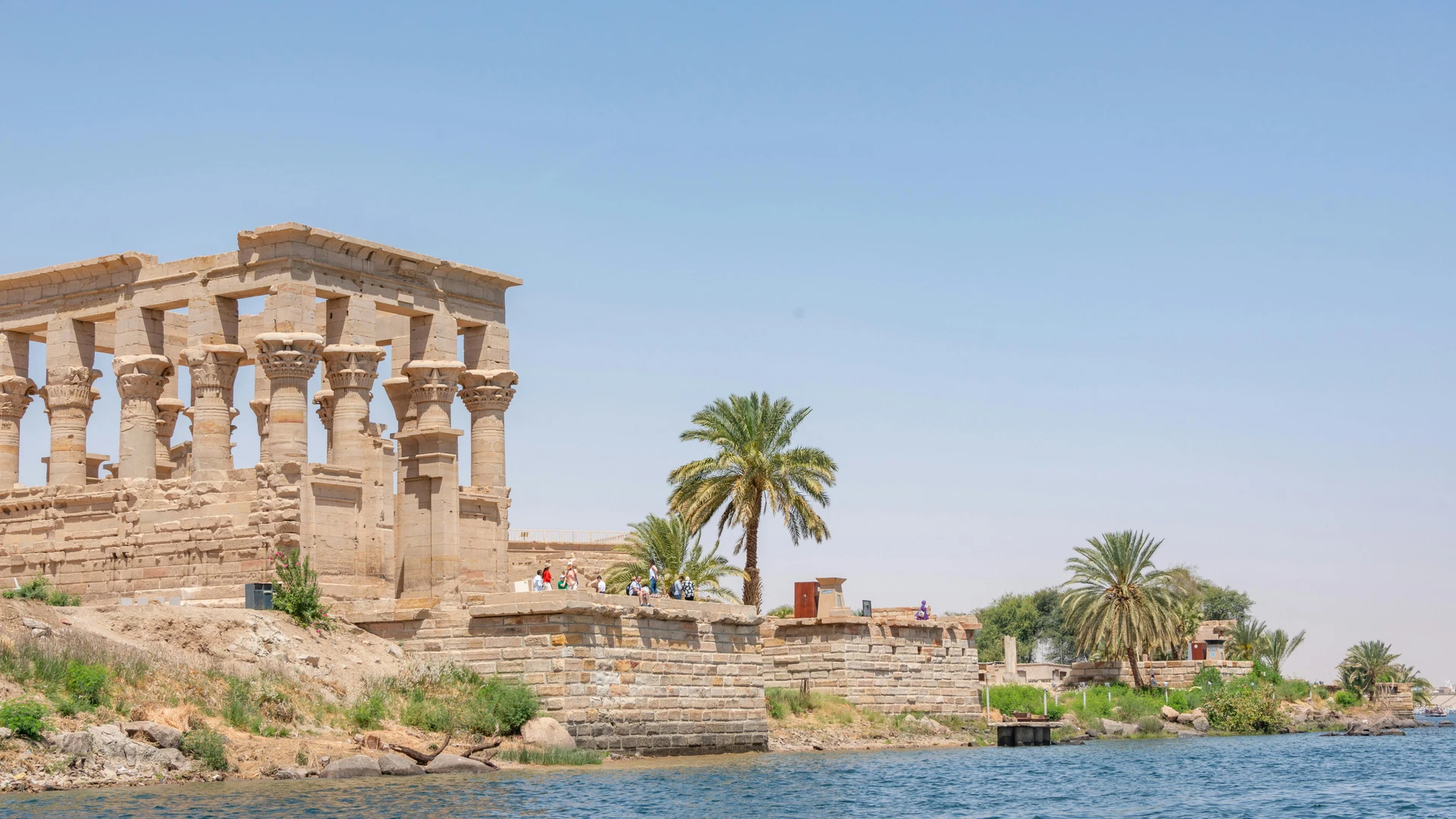 Aswan, Egypt - Ancient ruins of philae temple by the nile river under a clear blue sky.