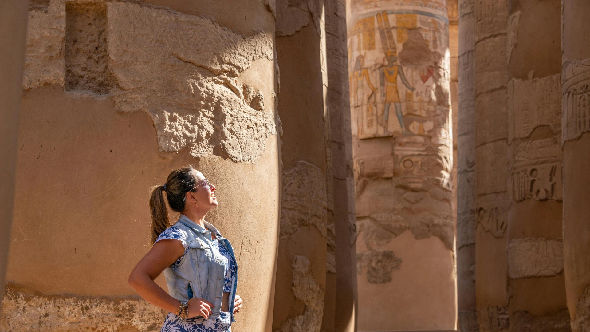 Marsa Alam, Egypt - Woman in luxor temple admiring ancient carved columns in sunlight.