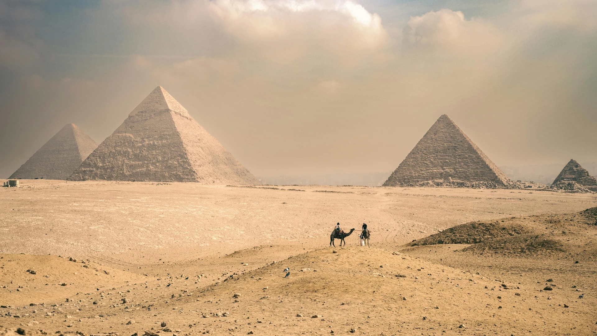 Sahl Hasheesh, Egypt - Explore the majestic pyramids of giza under a sunny sky with distant travelers on camels.