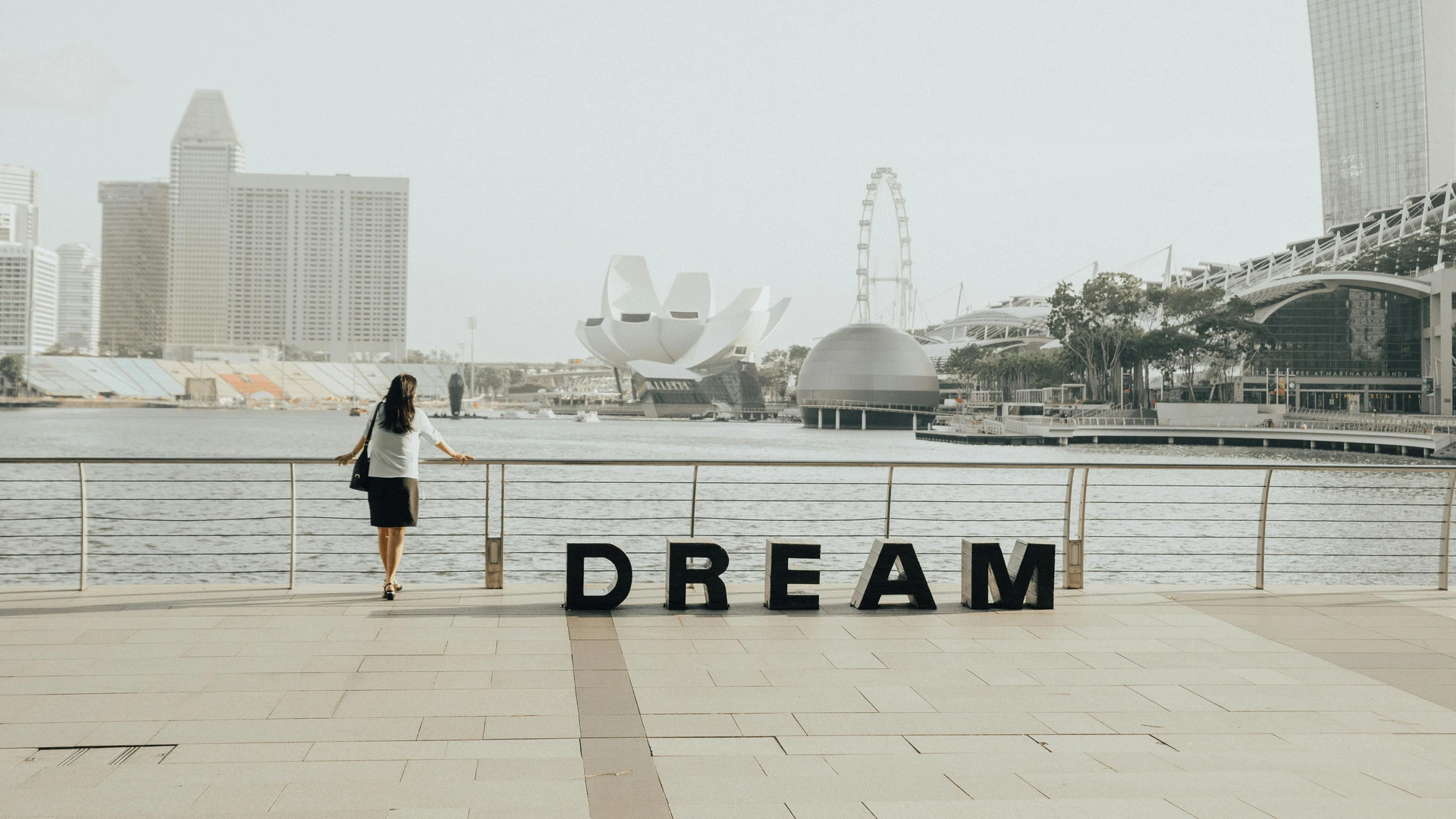 Soma Bay, Egypt - Woman gazing at the iconic marina bay sands skyline in singapore with 'dream' letters foregrounded.