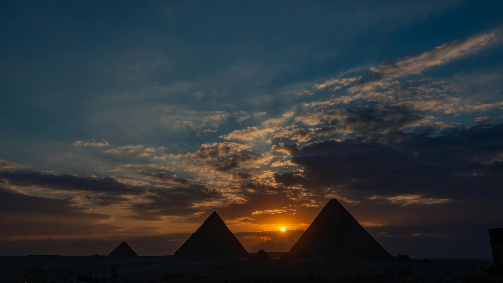 Cairo, Egypt - Silhouette of giza pyramids against a dramatic sunset sky.