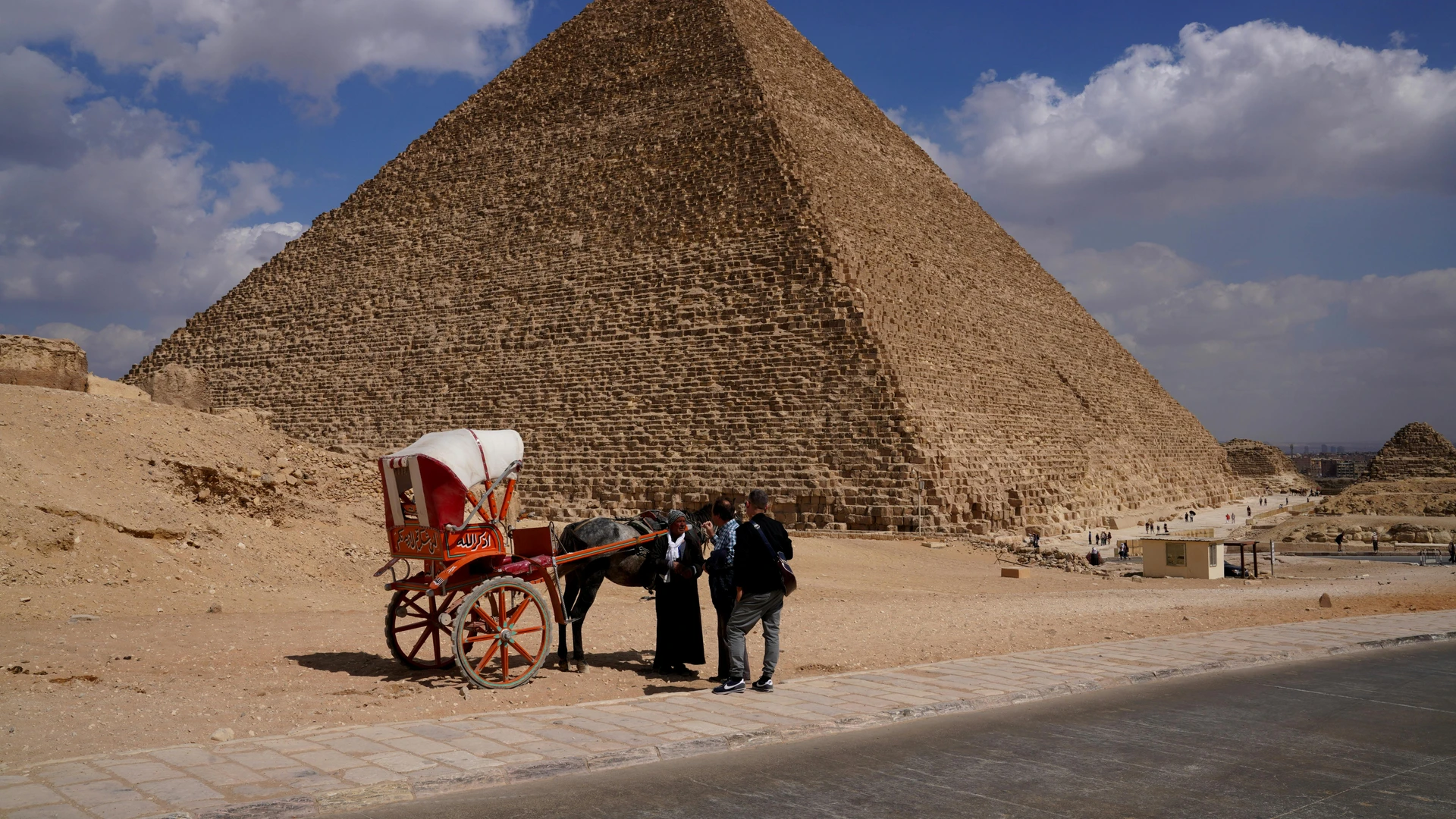 Giza, Egypt - Vivid capture of the great pyramid in giza, showcasing its grandeur with tourists and a traditional cart.