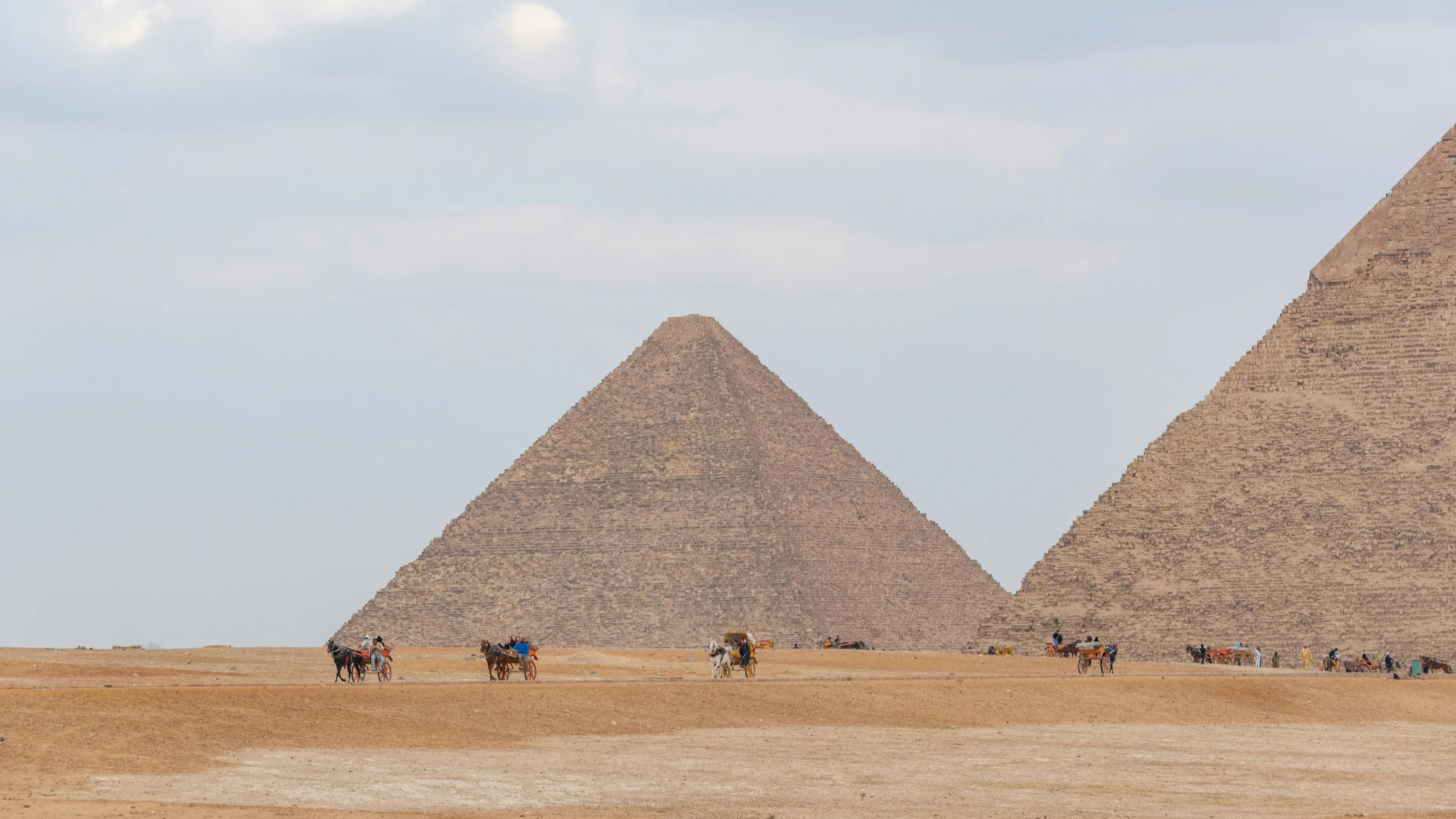 Hurghada, Egypt - Camel riders near the iconic pyramids of giza under a cloudy sky, showcasing egypt's historical allure.