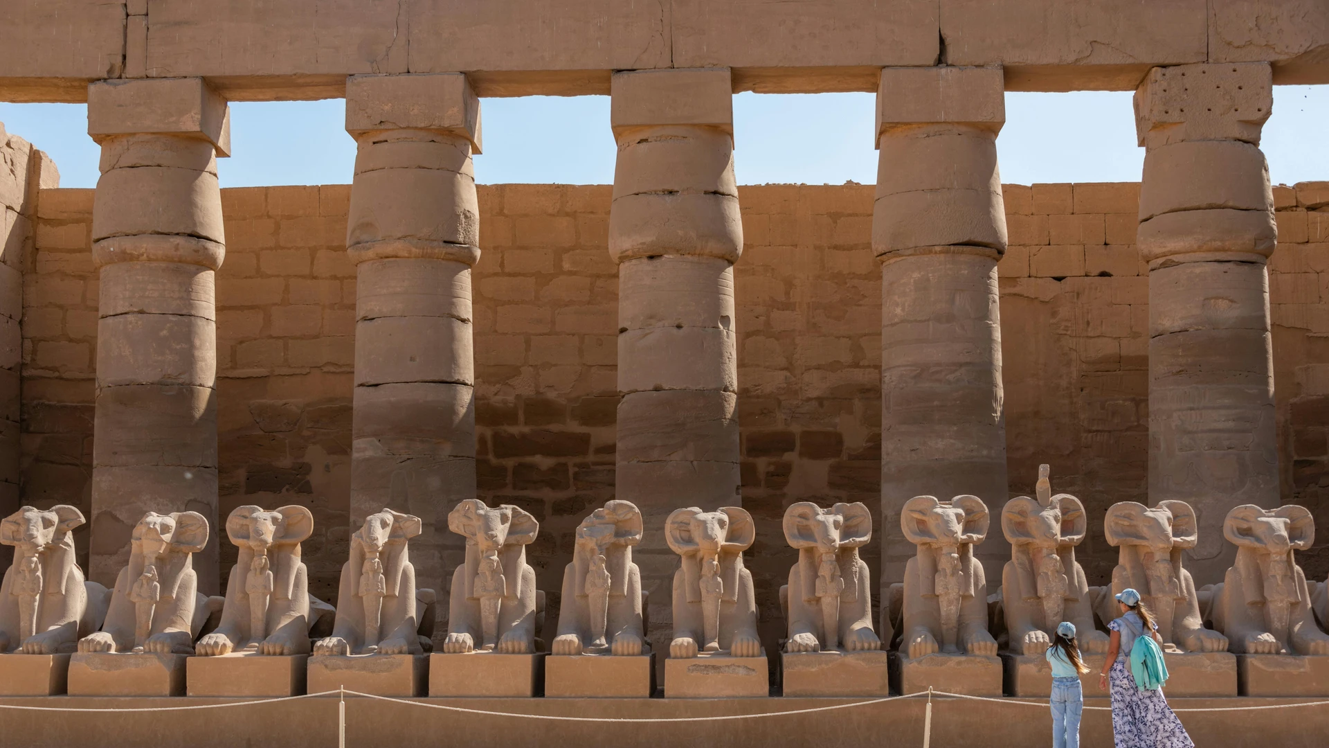 Luxor, Egypt - View of the ram-headed sphinx statues at karnak temple complex with visitors exploring the site.