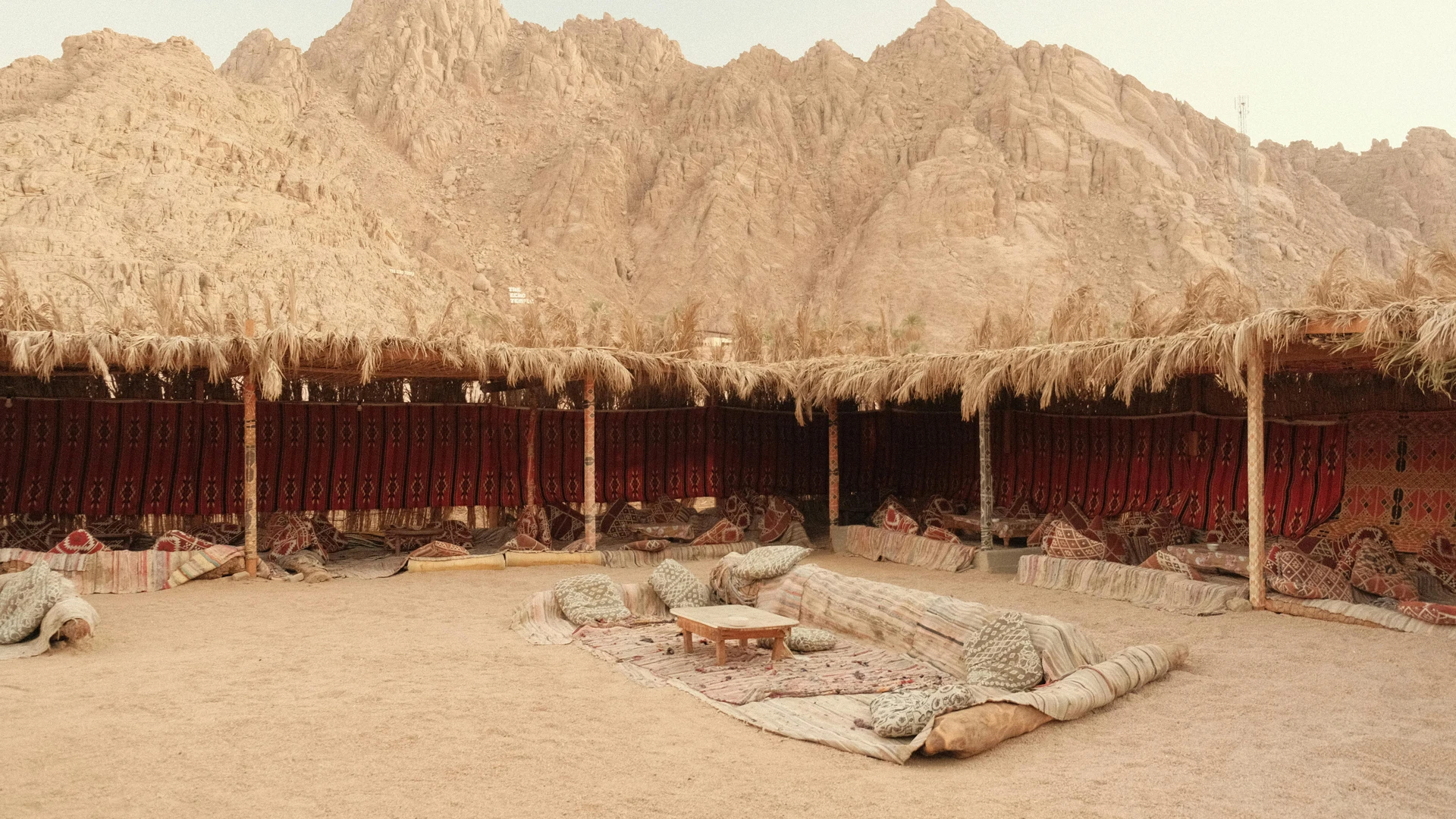 South Sinai, Egypt - Rustic tent with traditional decor set against a rugged mountain backdrop under a warm sky.